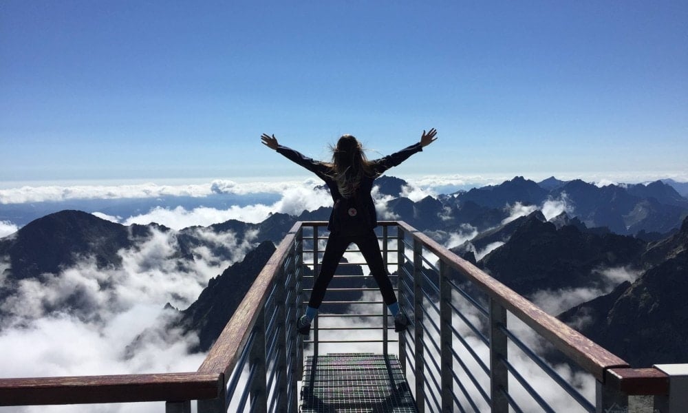 person standing on hand rails with arms wide open facing the 725255