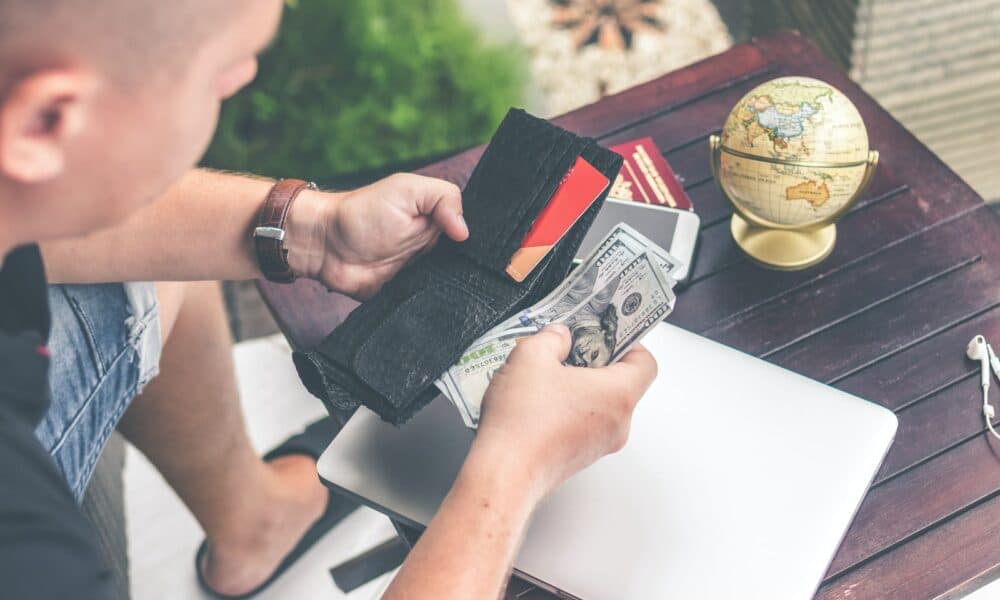 Man Holding U.s Dollar Banknotes and Black Leather Bi-fold Wallet