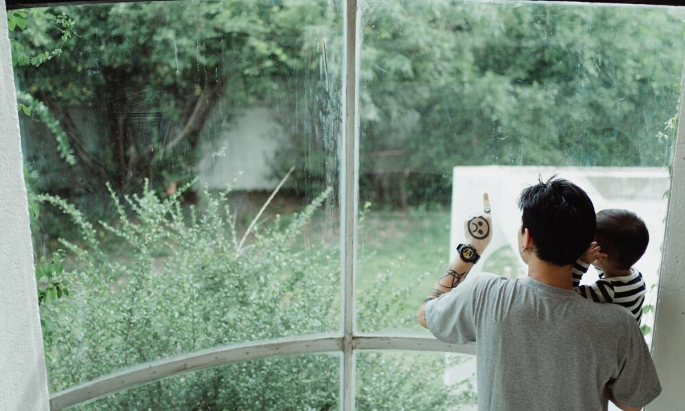 Father Carrying His Son and Pointing at Something Through the Window 