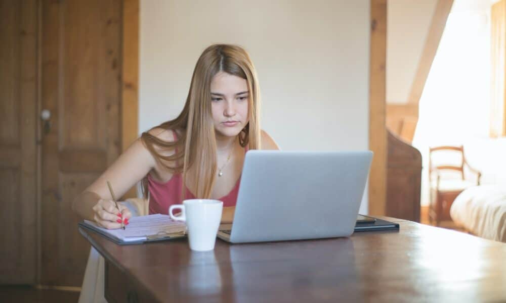 Woman in Brown Tank Top Sitting at the Table Using Macbook