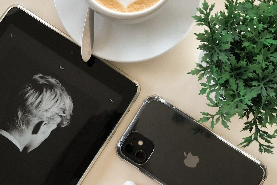 Black Iphone 11 Beside Airpods and Coffee Cup