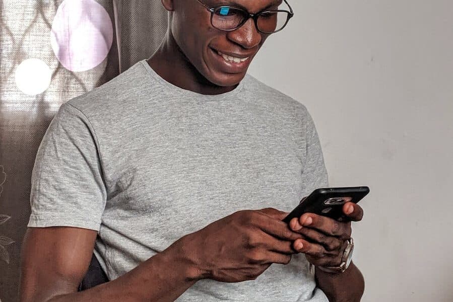 Man Wearing Gray Crew-neck Shirt Holding Black Smartphone