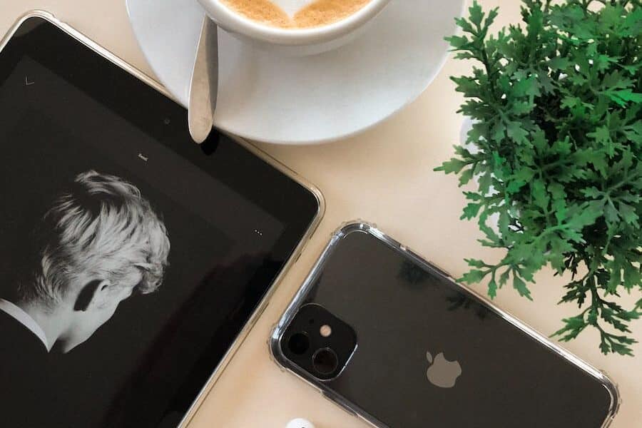 Black Iphone 11 Beside Airpods and Coffee Cup