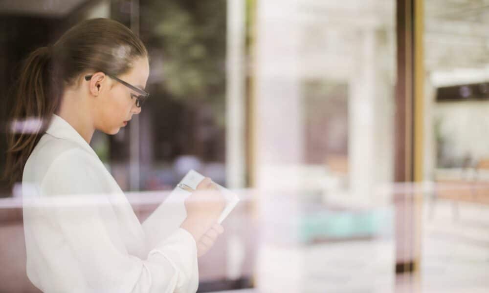 Side view of young concentrated businesswoman in formal clothing standing in office and writing ideas about startup project