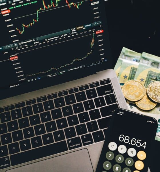 Bitcoins and Paper Money Beside a Cellphone and Laptop with Graphs on Screen