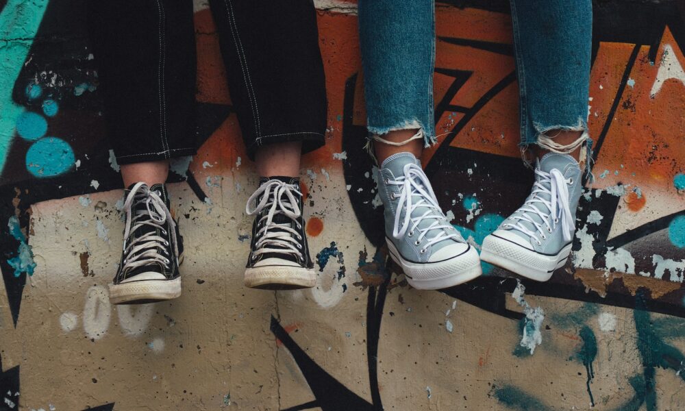person in blue denim jeans wearing black and white converse all star high top sneakers