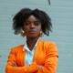 woman in orange blazer standing