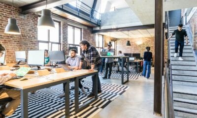 man standing beside another sitting man using computer