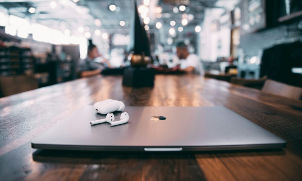 selective focus photography of white AirPods with charging case on silver MacBook on table