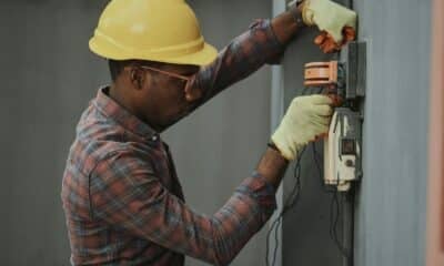 man in brown and white plaid dress shirt and yellow hard hat holding black and orange