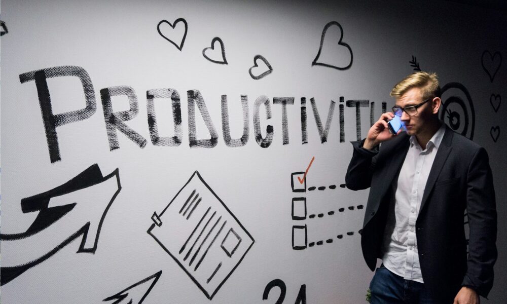 man holding smartphone looking at productivity wall decor