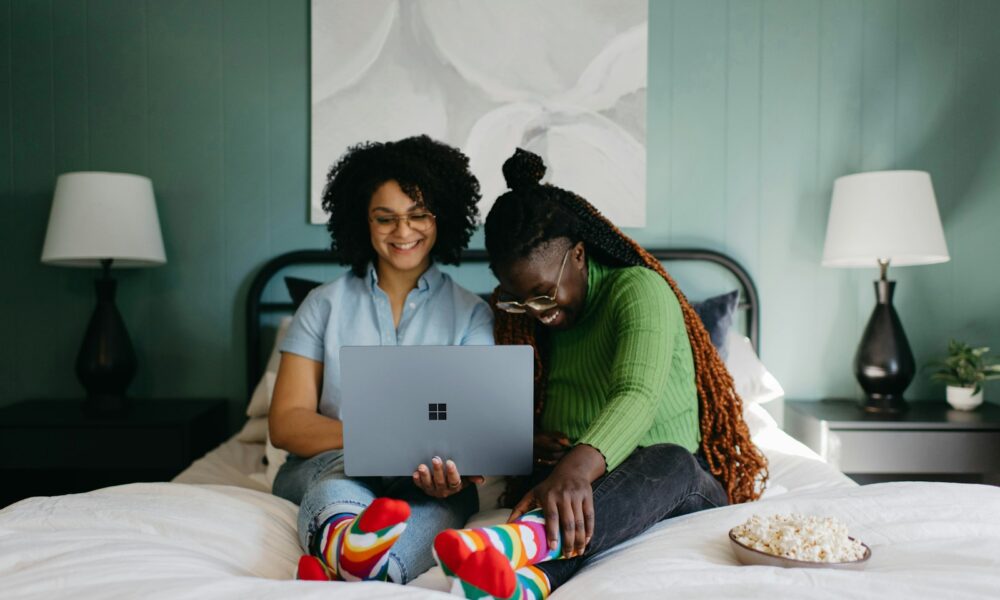 a woman sitting on a bed using a laptop
