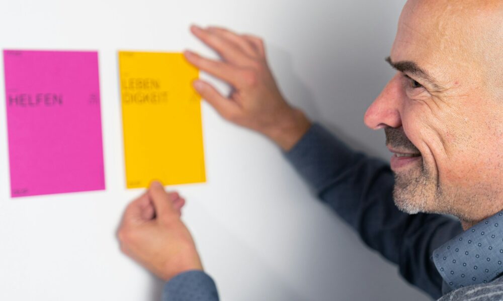 man in gray long sleeve shirt holding yellow sticky note
