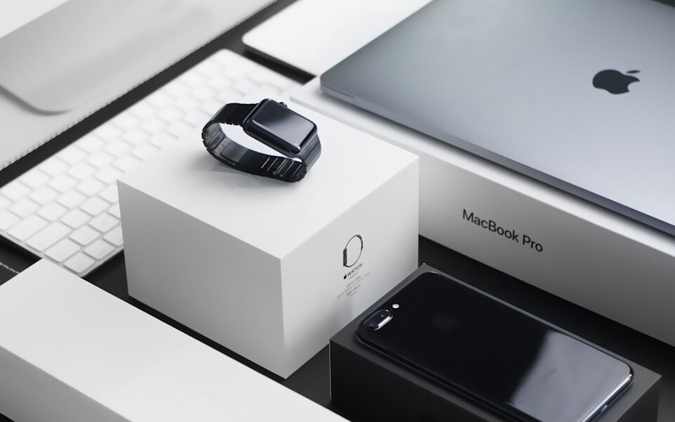 space black case Apple Watch, silver MacBook Pro, jet black iPhone 7 Plus, and silver iMac with corresponding boxes