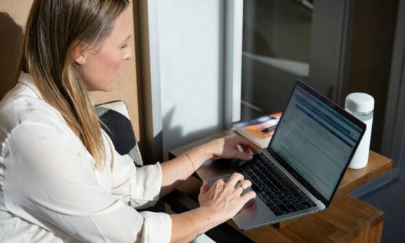 woman in white long sleeve shirt using black laptop computer
