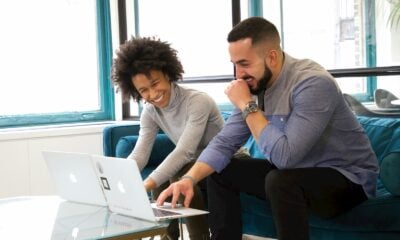 a man and woman sitting on a couch looking at a laptop