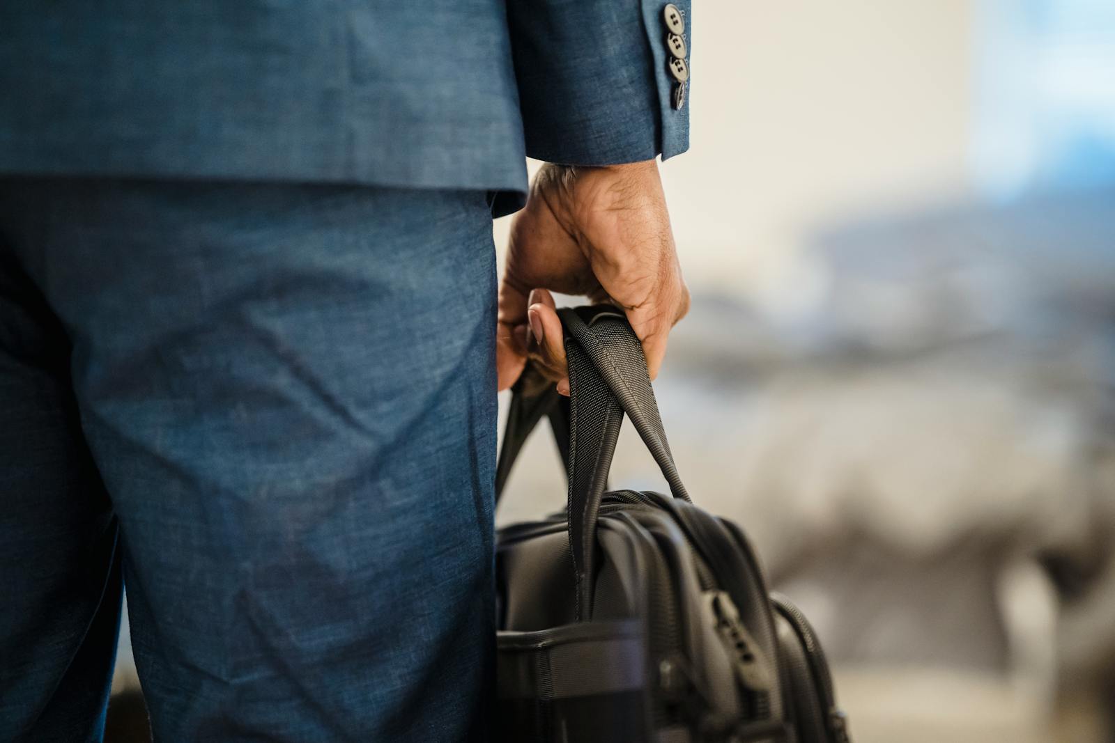 Close-up of a businessman's hand holding a briefcase, symbolizing professionalism.