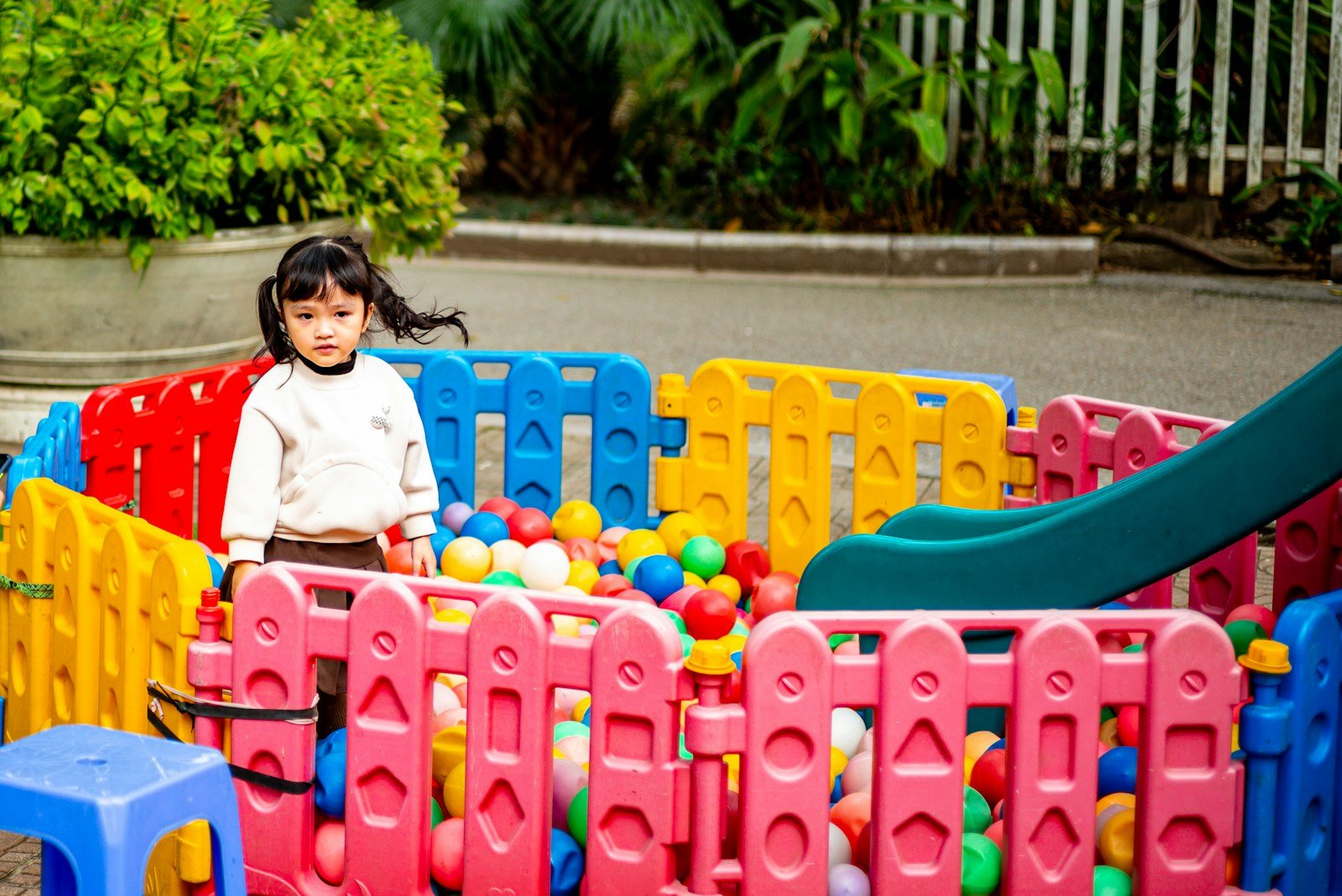 A little girl plays in a colorful ball pit.