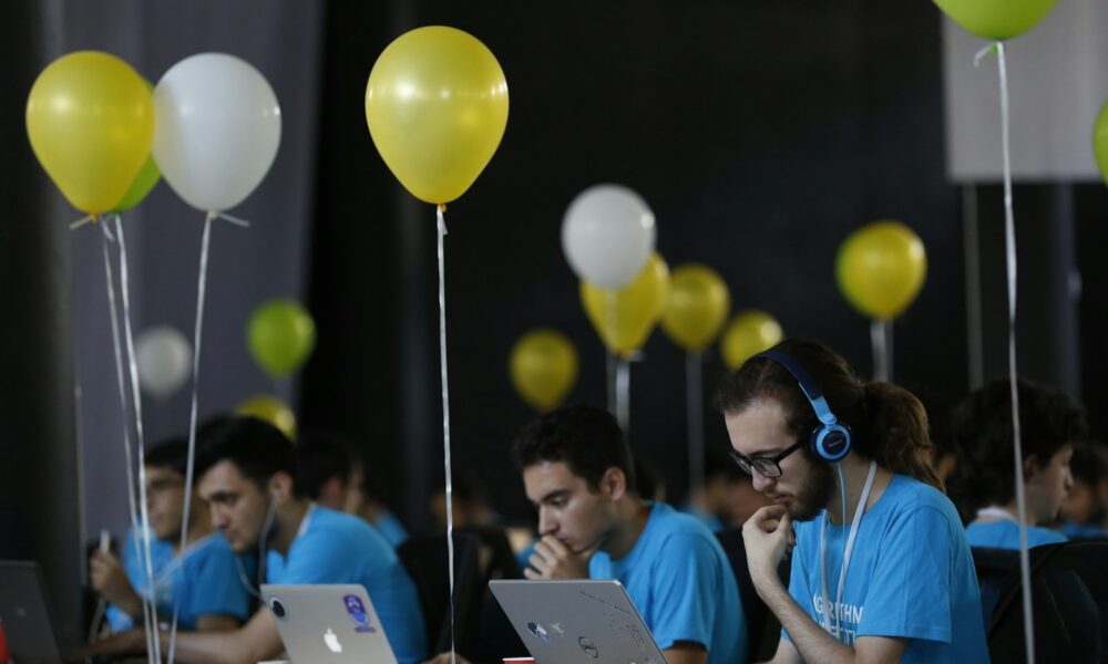 a group of people sitting at a table with laptops