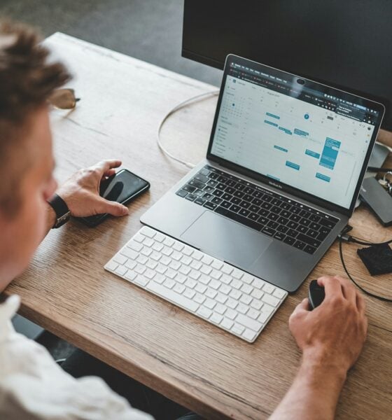 man holding mouse and iPhone while using Macbook Pro