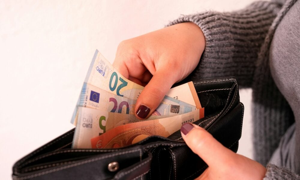 a woman is holding a wallet full of money