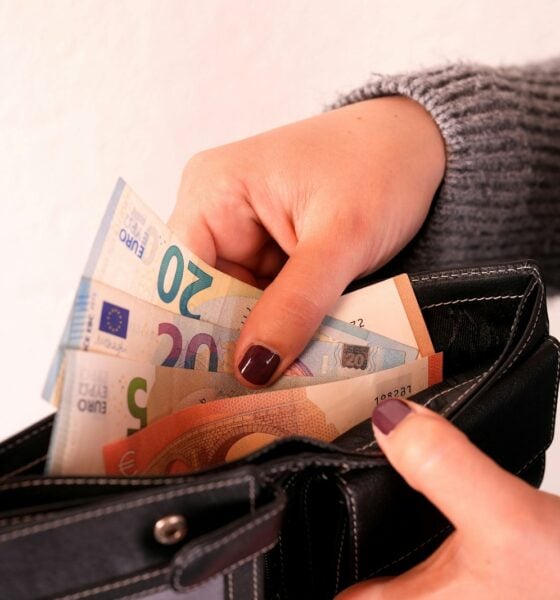 a woman is holding a wallet full of money