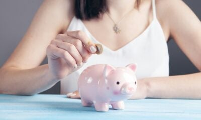 woman in white tank top holding pink pig figurine