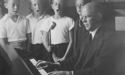a black and white photo of a man playing a piano