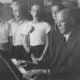 a black and white photo of a man playing a piano