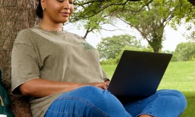 Woman using laptop while sitting under a tree