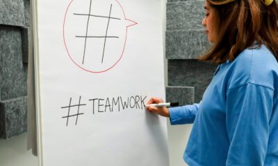a woman writing on a white board with a marker
