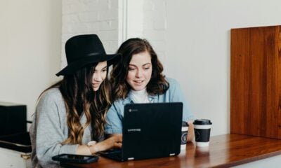 two woman sitting near table using Samsung laptop