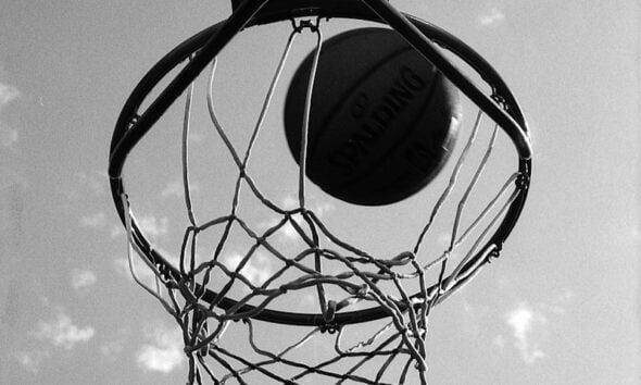 a black and white photo of a basketball going through the hoop