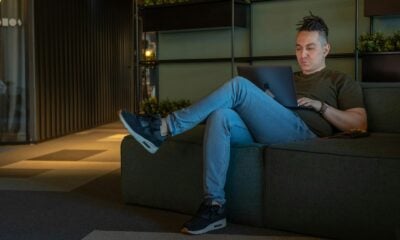 woman in gray long sleeve shirt and blue denim jeans sitting on gray couch