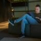 woman in gray long sleeve shirt and blue denim jeans sitting on gray couch