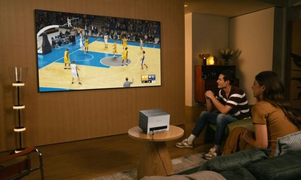 People watch a basketball game on a large screen.