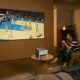 People watch a basketball game on a large screen.