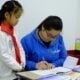 a woman and a girl are doing something on a desk
