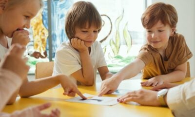 Young children engaging in fun learning activities at a yellow table in a classroom setting.