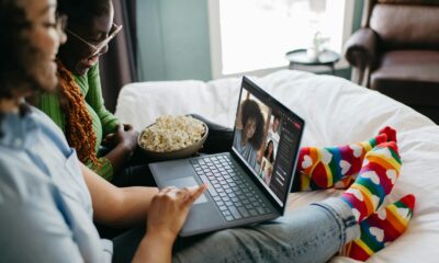 a couple of people sitting on a bed with a laptop