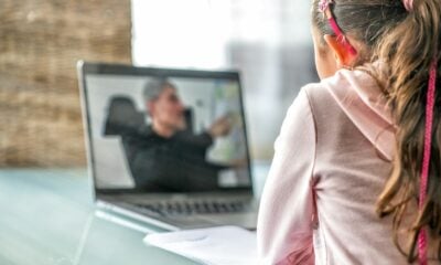 woman in pink long sleeve shirt sitting in front of macbook pro