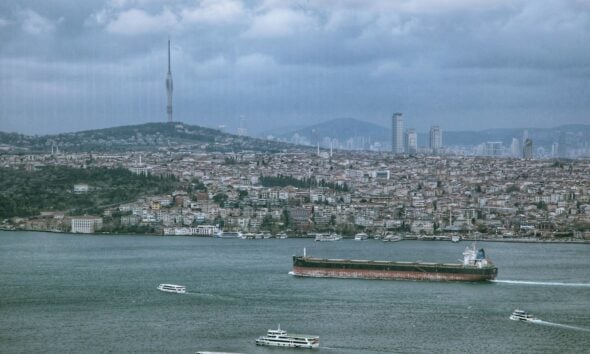 a large ship in the water with a city in the background