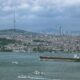 a large ship in the water with a city in the background