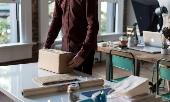 person holding cardboard box on table