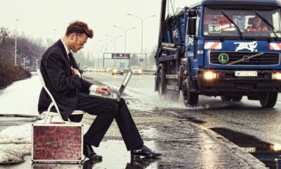 a man sitting on a suitcase on the side of the road