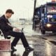 a man sitting on a suitcase on the side of the road