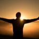 silhouette photo of man on cliff during sunset