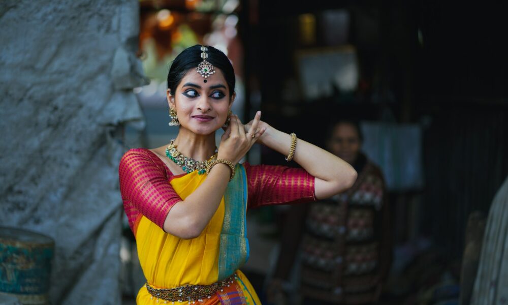 A woman in a yellow and red sari talking on a cell phone