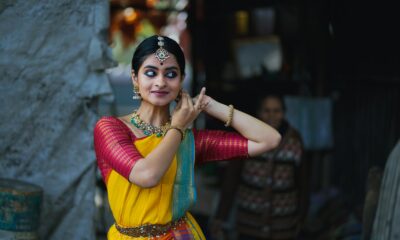 A woman in a yellow and red sari talking on a cell phone