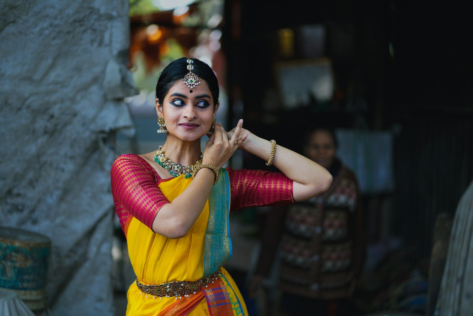 A woman in a yellow and red sari talking on a cell phone